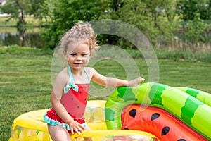 Cute little girl playing in an inflatable pool in the backyard