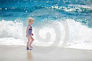 Cute little girl playing jumping over the waves