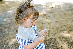 Cute little girl is playing with leaves in autumn park