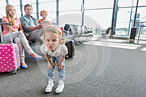 Cute little girl playing and making funny face in airport while waiting for boarding