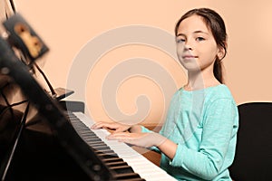 Cute little girl playing piano near wall. Music lesson