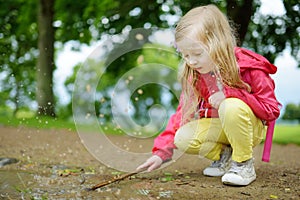 Cute little girl playing in a puddle on beautiful summer day outdoors