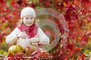 Cute little girl playing with pumpkins in autumn park. Autumn activities for children. Halloween and Thanksgiving time fun for