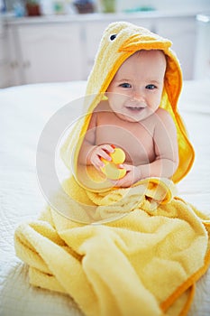 Cute little girl playing with rubber duck after having bath