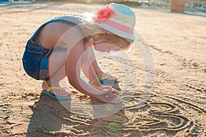 Cute little girl playing with sand on the beach