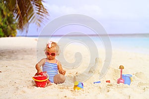 Cute little girl playing with sand on beach