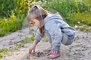 Cute little girl is playing with sand in the forest