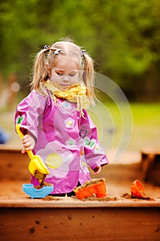 Cute little girl playing in a sandbox