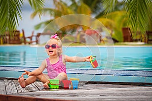 Cute little girl playing in swimming pool at tropical beach