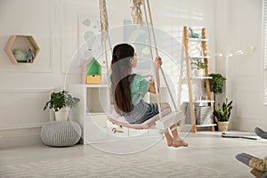 Cute little girl playing on swing at home photo