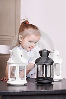 Cute little girl playing with three luminaires with candle photo