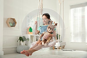 Cute little girl playing with toy deer on swing