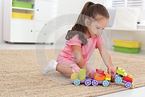 Cute little girl playing with toys on floor at home