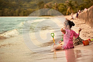 Cute little girl playing at tropical sea beach