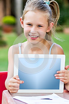 Cute little girl pointing at blank tablet outdoors.