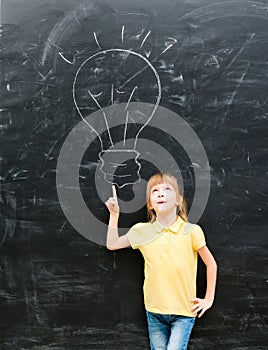 Cute little girl pointing on a drawn lamp