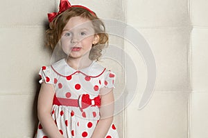 Cute little girl in a polka-dot dress with a red