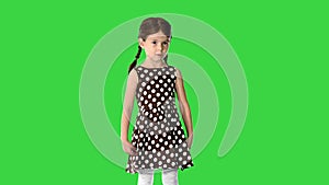 Cute little girl in polka dot dress talking about something to the camera on a Green Screen, Chroma Key.