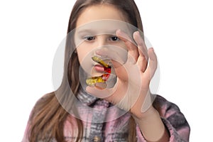 Cute little girl posing in the studio holding an orthodontic appliance in her hand. The concept of oral hygiene in childhood.