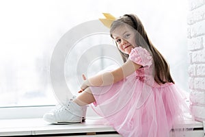 Cute little girl in a princess costume. Pretty child preparing for a costume party. Beautiful queen in gold crown.