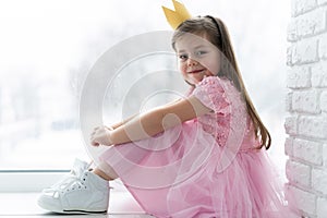 Cute little girl in a princess costume. Pretty child preparing for a costume party. Beautiful queen in gold crown.