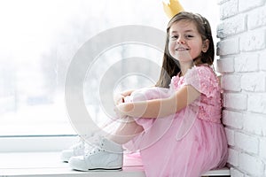Cute little girl in a princess costume. Pretty child preparing for a costume party. Beautiful queen in gold crown.