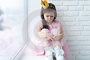 Cute little girl in a princess costume. Pretty child preparing for a costume party. Beautiful queen in gold crown.