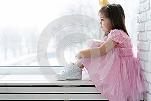 Cute little girl in a princess costume. Pretty child preparing for a costume party. Beautiful queen in gold crown.