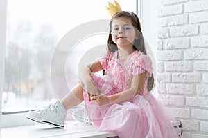 Cute little girl in a princess costume. Pretty child preparing for a costume party. Beautiful queen in gold crown.