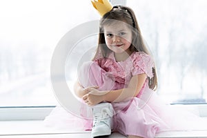 Cute little girl in a princess costume. Pretty child preparing for a costume party. Beautiful queen in gold crown.