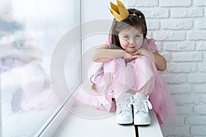 Cute little girl in a princess costume. Pretty child preparing for a costume party. Beautiful queen in gold crown.