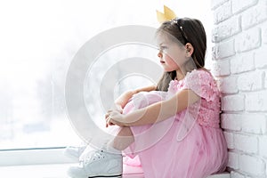 Cute little girl in a princess costume. Pretty child preparing for a costume party. Beautiful queen in gold crown.