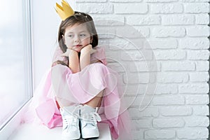 Cute little girl in a princess costume. Pretty child preparing for a costume party. Beautiful queen in gold crown.