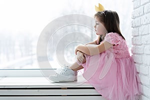 Cute little girl in a princess costume. Pretty child preparing for a costume party. Beautiful queen in gold crown.