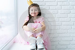 Cute little girl in a princess costume. Pretty child preparing for a costume party. Beautiful queen in gold crown.