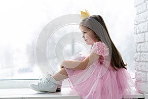 Cute little girl in a princess costume. Pretty child preparing for a costume party. Beautiful queen in gold crown.