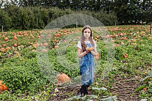 Cute little girl with pumpkin in hands in a pumpkin patch