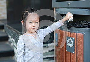 Cute little girl putting waste in the bin outdoor