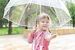 cute little girl on a rainy summer day under a transparent umbrella