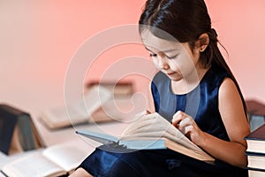 Cute little girl is reading a book.