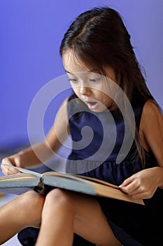 Cute little girl is reading a book.