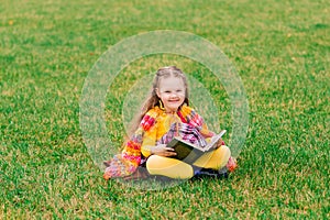 Cute little girl reading a book in autumn park