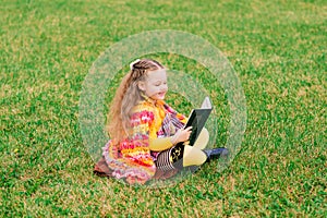 Cute little girl reading a book in autumn park