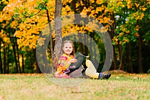 Cute little girl reading a book in autumn park