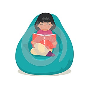 Cute little girl reading book in bean bag.