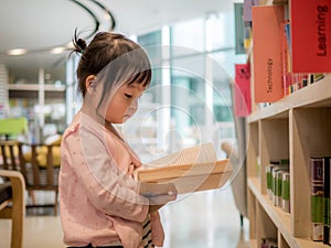 Cute little girl reading book in the library, this image can use for education