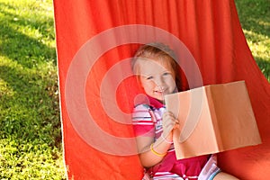 Cute little girl reading book in park on sunny day