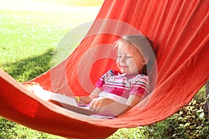 Cute little girl reading book in park on sunny day