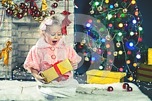 Cute little girl receive a gift near decorating Christmas tree.