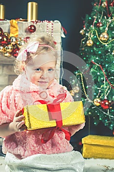 Cute little girl receive a gift near decorating Christmas tree.